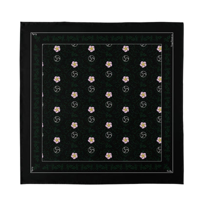 A top-down, flat lay view of the 'Kinky' hanky code bandana. The square black fabric features the all-over BDSM vine pattern with pink flowers and the word 'Kinky' written in the border.
