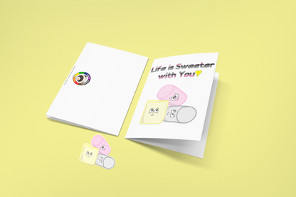 Two greeting cards on a yellow background. The first is flipped to show the back, with the Ninja Ferret Logo. The second has a white background. At the top is the text, "Life is Sweeter with You!" in the queerplatonic pride flag colours. Below are matching pink, yellow, and grey cartoon marshmallows with cute expressions. Below the cards is a matching sticker of three marshmallows.